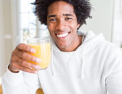 person smiling and drinking a glass of juice