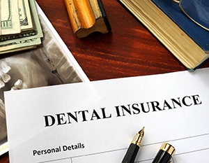 Dental insurance paperwork on wooden desk with pens