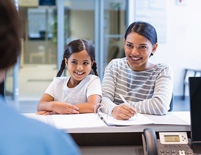 Mother and daughter checking in at reception desk