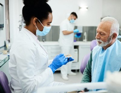 : A dentist showing a patient artificial dentures 