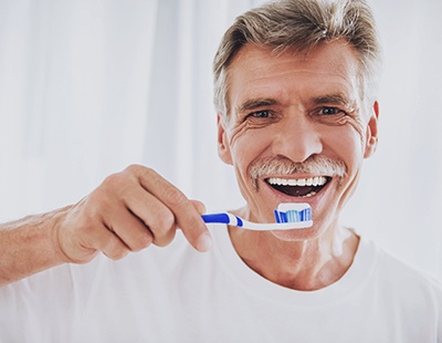 Man with dentures brushing teeth