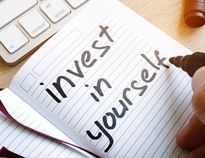 a note pad with the word “invest in yourself” written in it