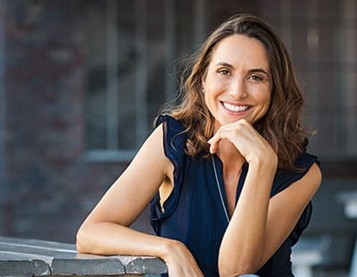 a smiling person with their chin resting on their hand