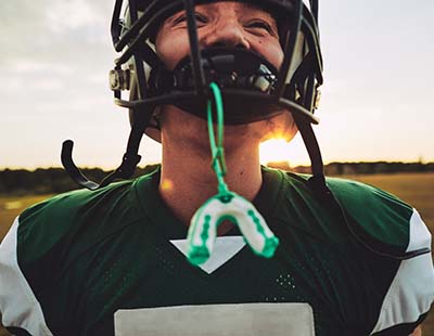 Boy wearing mouthguard to prevent dental emergencies in Frederick