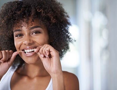 woman flossing to alleviate her dental emergency in Frederick 