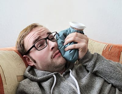 man holding cold compress to his face