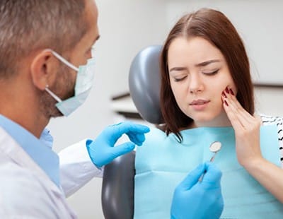 young woman in pain talking to her dentist 