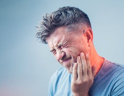 man holding his mouth in pain 