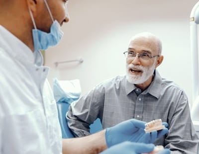 An older man speaking with his dentist about dental implant aftercare in Frederick