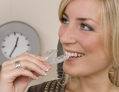 Woman holding aligner from Invisalign dentist in Frederick 