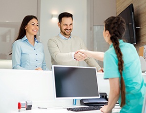 Man and woman smiling with a dental employee