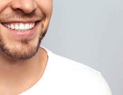 Man smiling in front of a gray background