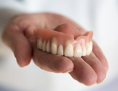 Hand holding a full denture