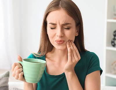 Woman with her hand on her mouth experiencing dental pain