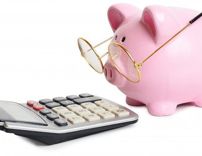 Piggy bank with glasses looking at a calculator 
