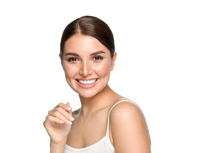 A young woman wearing a white tank top and smiling to show off her new veneers