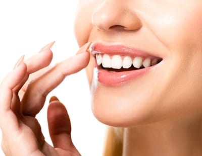 An up-close look at a woman touching her smile that contains new and natural veneers