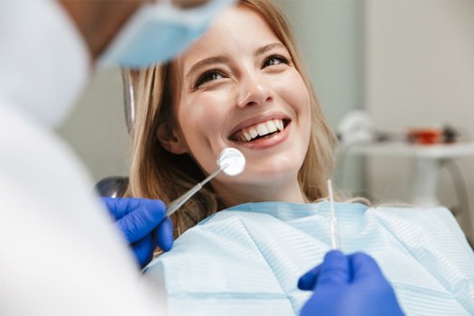 Blond woman in dental chair smiling at dentist