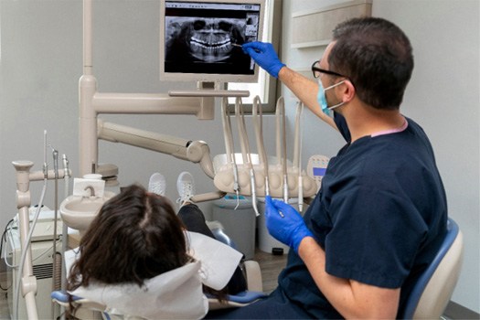 Dentist in blue scrubs showing patient her X-rays