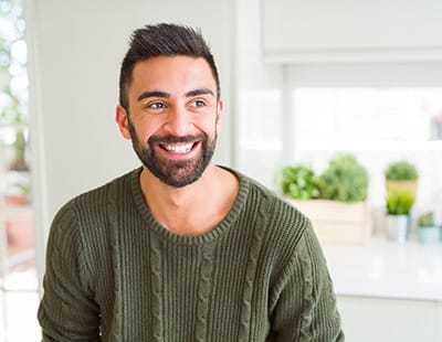 person smiling and standing in a kitchen