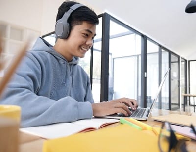 teenager working on their laptop in a library