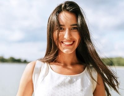 person smiling and walking on a beach