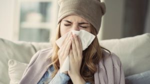 woman blowing her nose during cold and flu season in Frederick 
