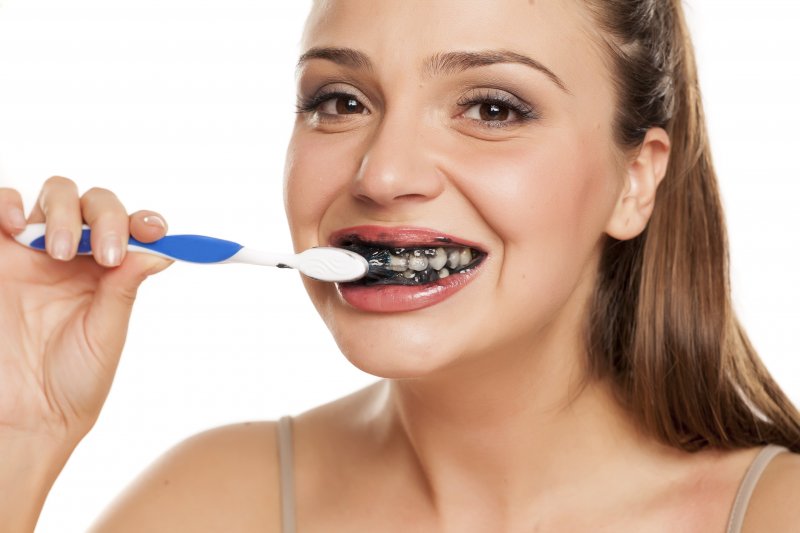 Woman brushing her teeth with charcoal