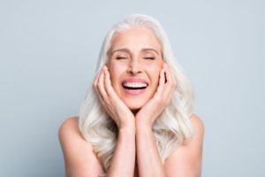 a woman smiling and placing her hands on her face