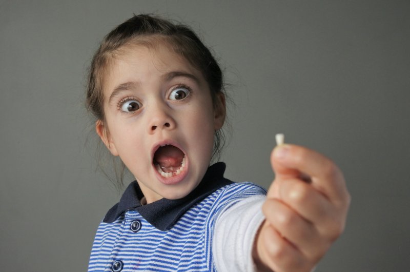 child holding a tooth that they’ve lost