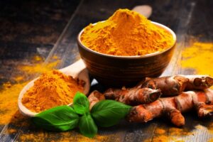 Powered turmeric next to whole turmeric root