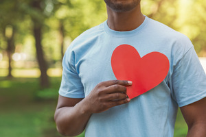 Close-up of man holding paper heart over his chest